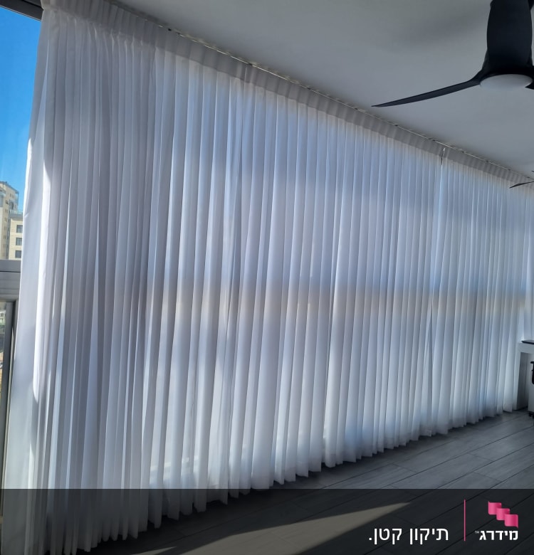 וילונות לבנים תלויים על חלון גדול